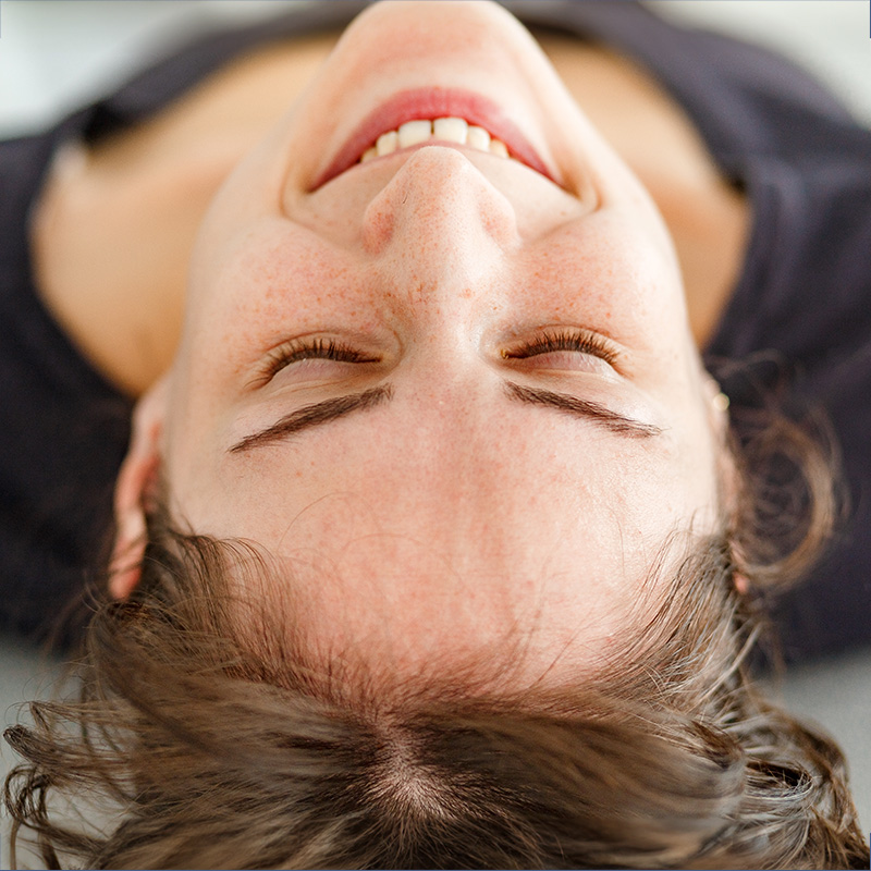 Woman lying on her back with her eyes closed during a breathwork sessopm